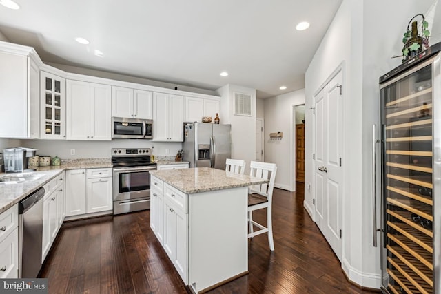 435 Potomac Run Rd, Fredericksburg, VA 22405 - kitchen with appliances with stainless steel finishes, beverage cooler, a breakfast bar, glass insert cabinets, and white cabinetry