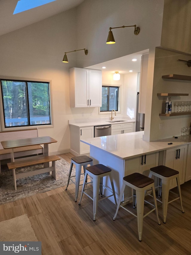 6 Granby Ln, Ocean Pines, MD 21811 - kitchen with stainless steel dishwasher, a sink, white cabinets, wood finished floors, and high vaulted ceiling