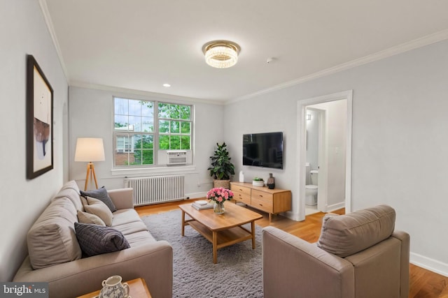 living room featuring radiator heating unit, ornamental molding, light wood-type flooring, baseboards, and cooling unit