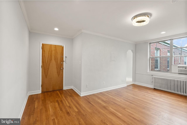unfurnished room with radiator heating unit, crown molding, light wood-style flooring, baseboards, and recessed lighting