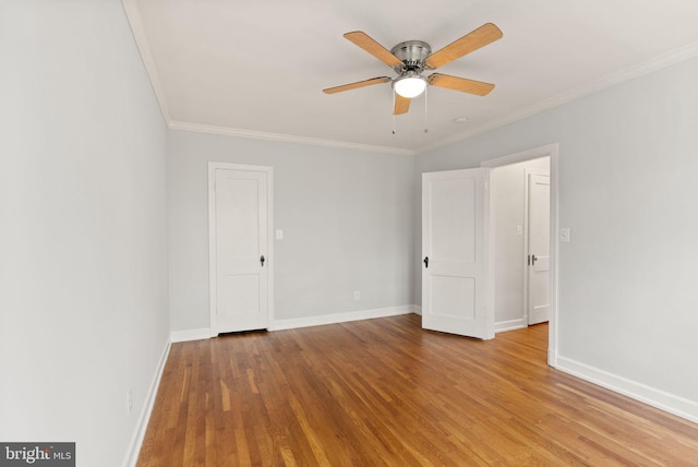 unfurnished bedroom featuring wood finished floors, ornamental molding, baseboards, and a ceiling fan