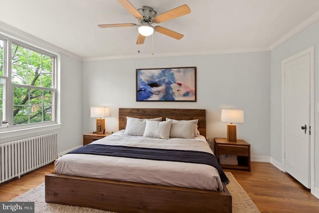 bedroom featuring radiator heating unit, wood finished floors, baseboards, ornamental molding, and ceiling fan