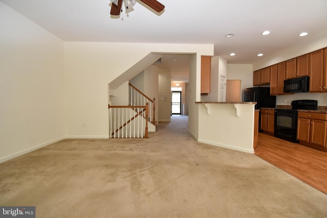 10020 Iron Pointe Dr Unit 9D, Millsboro, DE 19966 - kitchen with black appliances, brown cabinetry, a breakfast bar area, recessed lighting, and light carpet