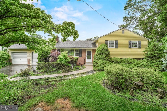 split level home featuring a chimney, driveway, brick siding, and a shingled roof