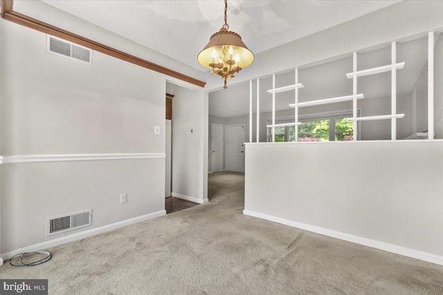 carpeted empty room featuring baseboards and a chandelier