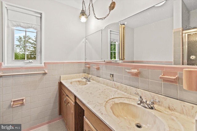 full bathroom featuring tile walls, a wainscoted wall, double vanity, an enclosed shower, and tile patterned floors