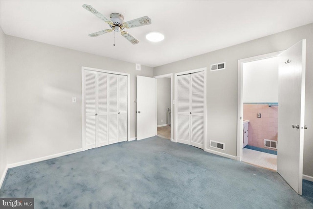 unfurnished bedroom featuring multiple closets, carpet, ensuite bath, tile walls, and baseboards