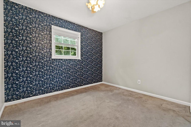 carpeted empty room featuring wallpapered walls and baseboards