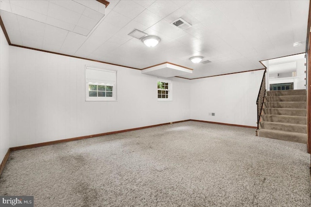 basement featuring baseboards, stairs, carpet floors, and crown molding