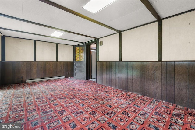 empty room with baseboard heating, wooden walls, and a wainscoted wall