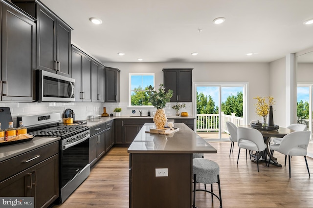 kitchen featuring stainless steel appliances, tasteful backsplash, a kitchen bar, a sink, and a kitchen island