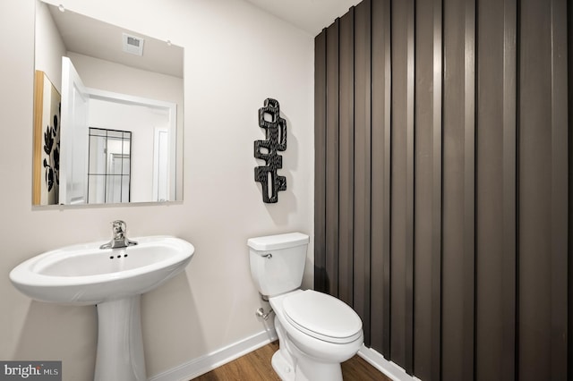 bathroom with baseboards, wood finished floors, toilet, and a sink