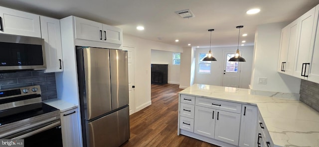 kitchen featuring appliances with stainless steel finishes, a peninsula, white cabinets, dark wood finished floors, and backsplash