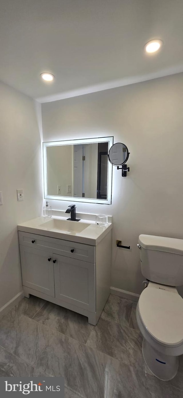 bathroom featuring baseboards, toilet, vanity, recessed lighting, and marble look tile flooring
