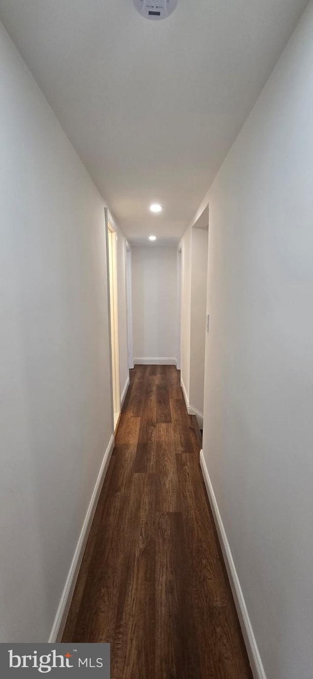corridor with baseboards, wood finished floors, and recessed lighting