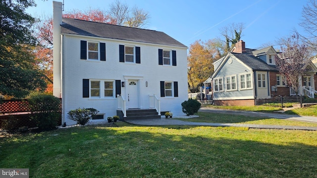 view of front of property featuring brick siding, a chimney, and a front lawn
