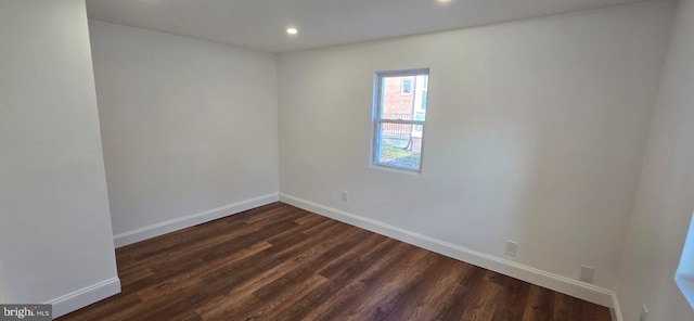 spare room with recessed lighting, baseboards, and dark wood finished floors