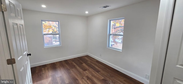 empty room with dark wood-style flooring, baseboards, and recessed lighting