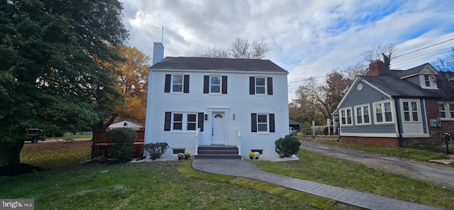 view of front facade with a chimney, a front lawn, and driveway