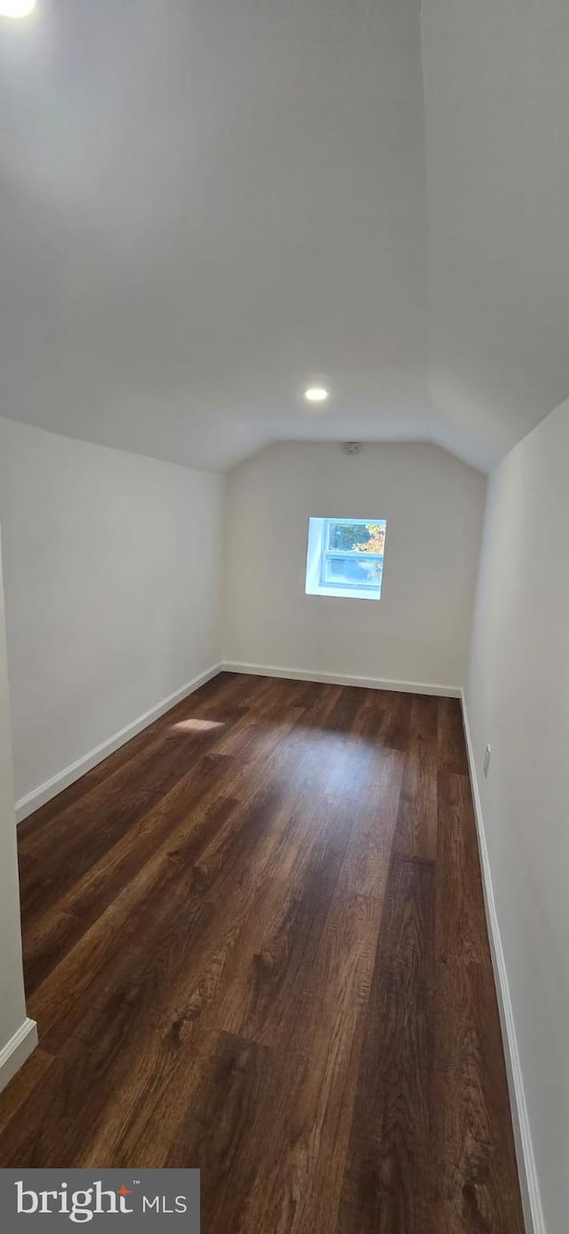 bonus room featuring lofted ceiling, dark wood-style floors, and baseboards
