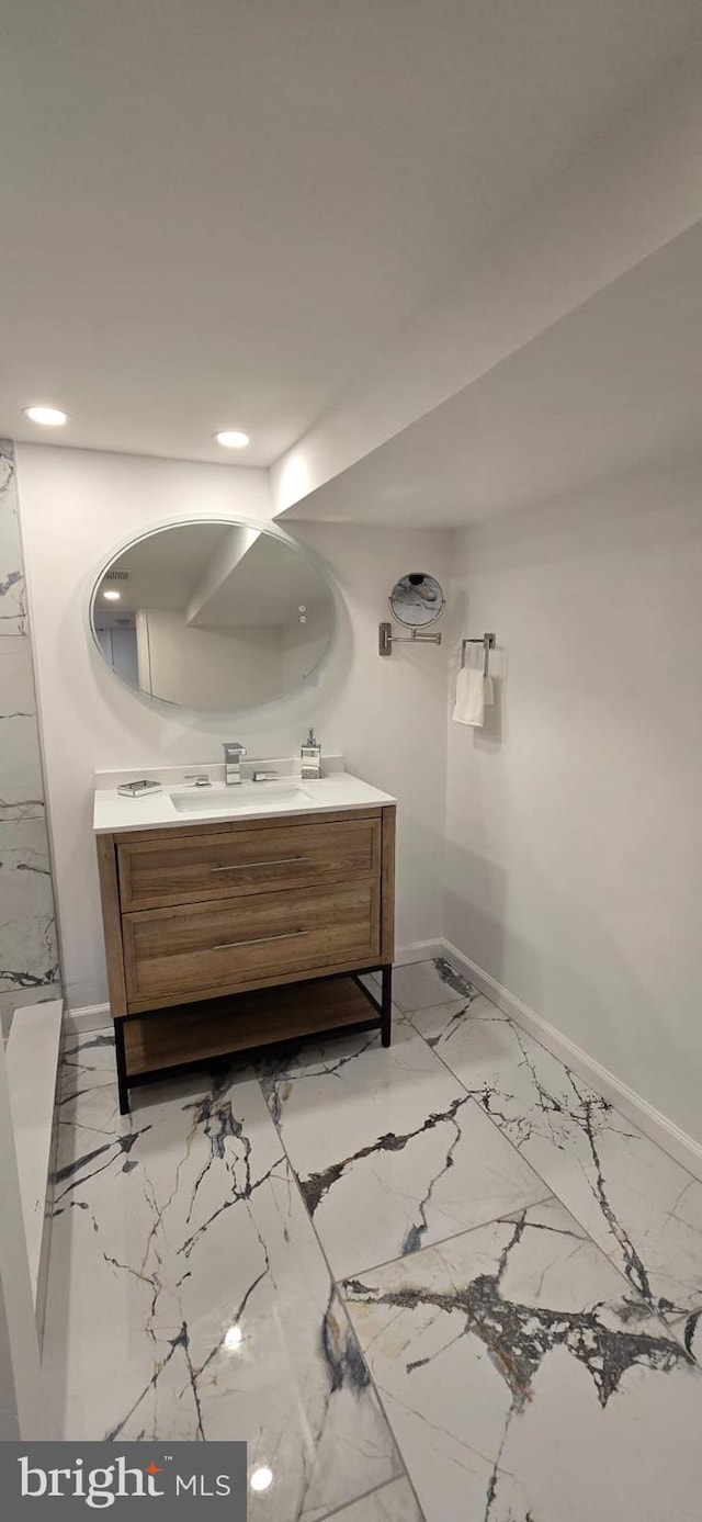bathroom with baseboards, marble finish flooring, recessed lighting, and double vanity