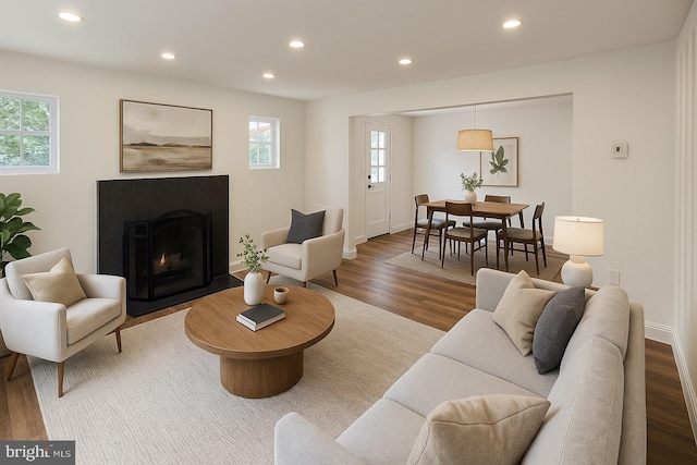 living room with wood finished floors, recessed lighting, a fireplace with flush hearth, and baseboards