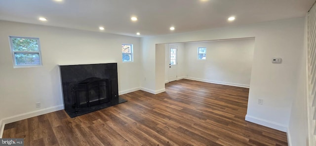 unfurnished living room with healthy amount of natural light, dark wood-style floors, recessed lighting, and baseboards