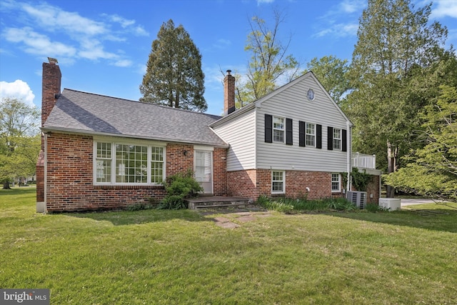 tri-level home featuring a chimney, a front yard, and brick siding