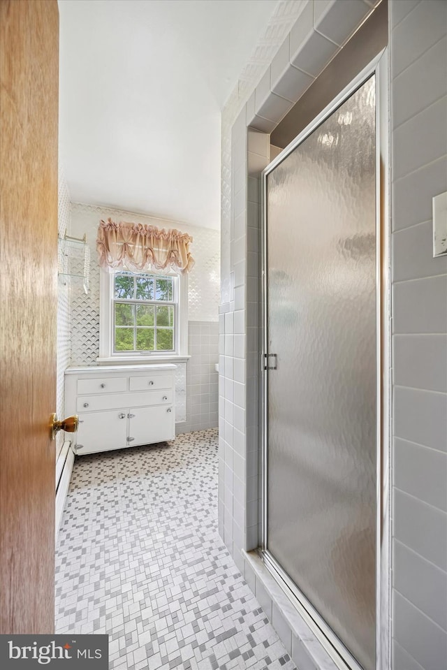full bath with a shower stall, tile patterned floors, tile walls, and a baseboard radiator