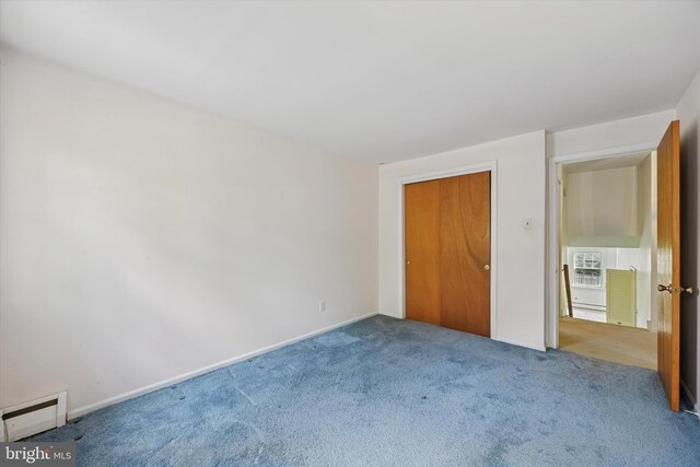 unfurnished bedroom with baseboard heating, carpet floors, baseboards, and a closet