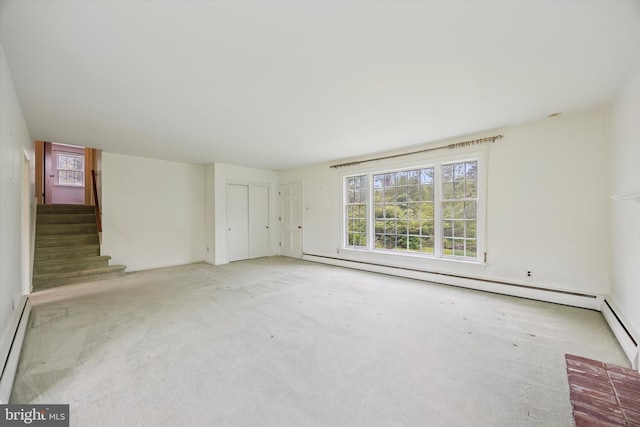 unfurnished living room featuring baseboard heating, carpet, and healthy amount of natural light