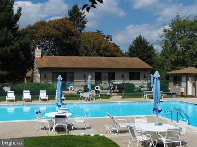community pool with a patio and fence