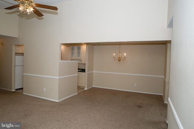 unfurnished room with light carpet, ceiling fan, a chandelier, a high ceiling, and baseboards
