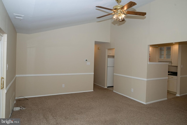 empty room with carpet floors, a ceiling fan, high vaulted ceiling, and baseboards