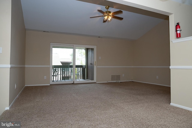 carpeted spare room featuring a ceiling fan, vaulted ceiling, and baseboards