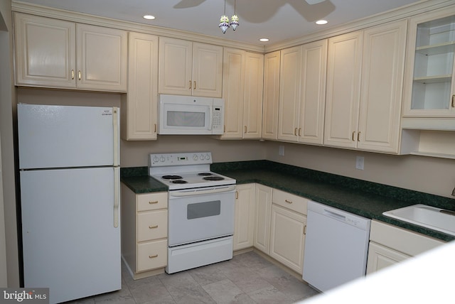 kitchen with white appliances, a sink, cream cabinetry, dark countertops, and recessed lighting
