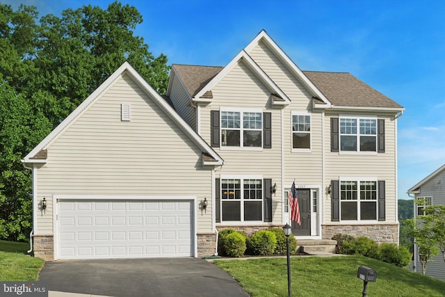 view of front of home featuring driveway, a front lawn, stone siding, and a shingled roof