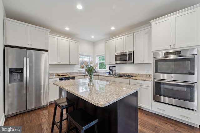 kitchen featuring appliances with stainless steel finishes, dark wood-style floors, recessed lighting, a center island, and white cabinetry
