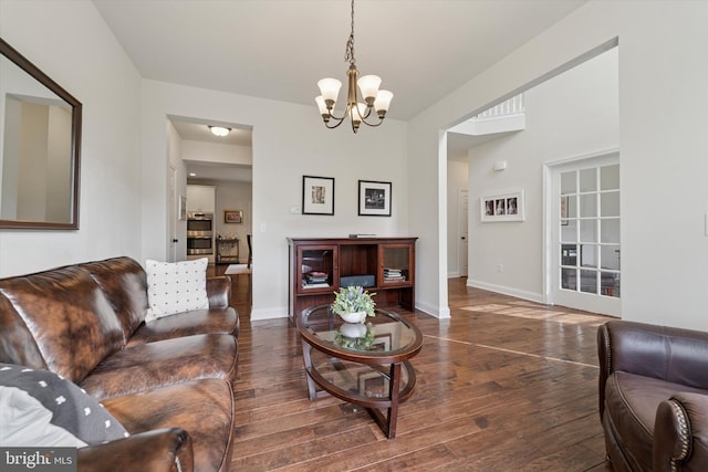 living room featuring a chandelier, hardwood / wood-style floors, and baseboards