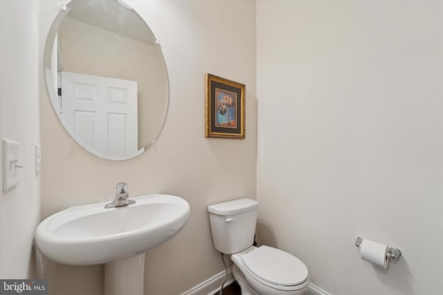 bathroom with toilet, baseboards, and a sink