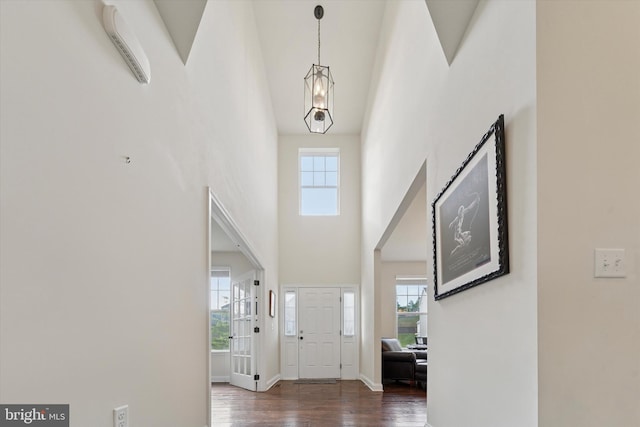 entryway featuring a towering ceiling, wood finished floors, a chandelier, and baseboards