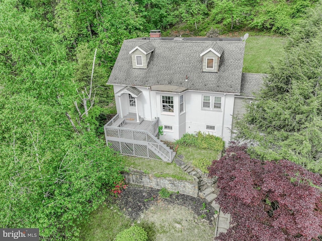 view of front of house featuring roof with shingles, stucco siding, a chimney, and stairway