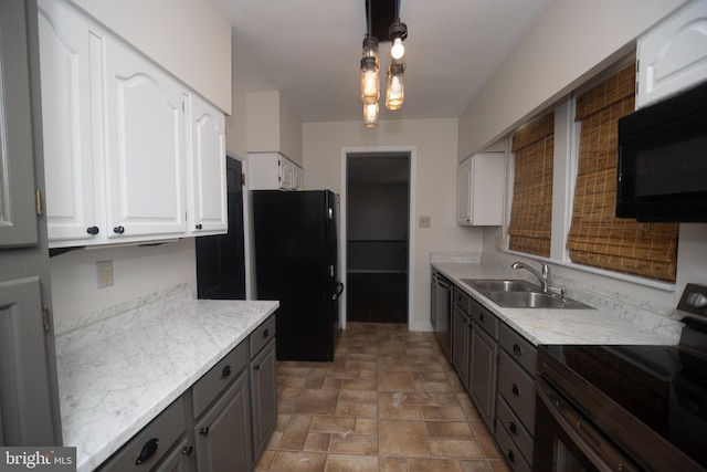 kitchen featuring black appliances, a sink, gray cabinetry, white cabinetry, and stone finish floors