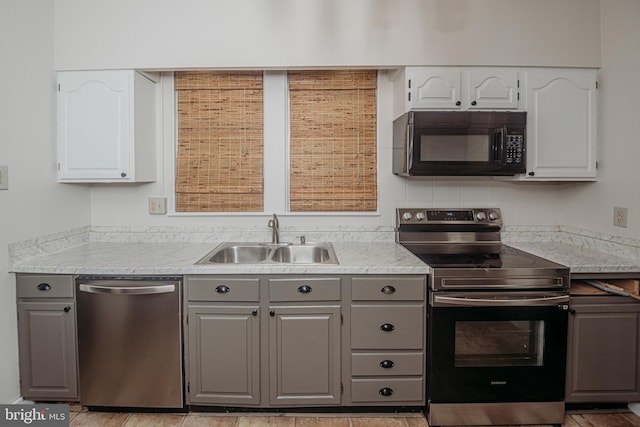 kitchen featuring stainless steel appliances, gray cabinets, a sink, and white cabinetry