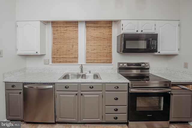kitchen featuring appliances with stainless steel finishes, a sink, gray cabinets, and white cabinets