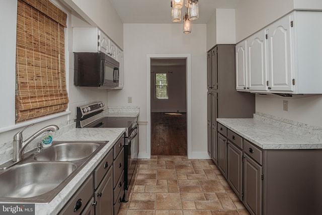 kitchen featuring stainless steel electric range, black microwave, a sink, and white cabinets