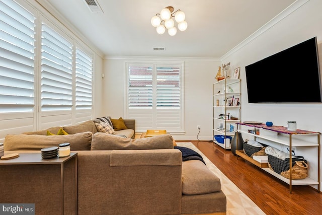 living area with wood finished floors, crown molding, baseboards, and a chandelier
