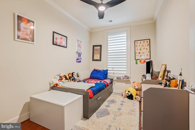 bedroom featuring baseboards, crown molding, a ceiling fan, and wood finished floors
