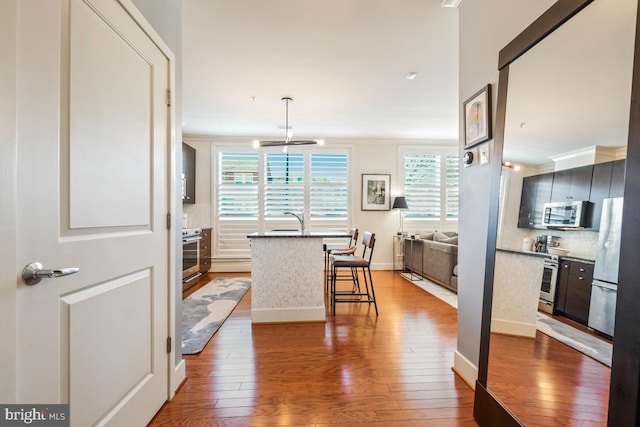 dining area with healthy amount of natural light, hardwood / wood-style floors, ornamental molding, and baseboards