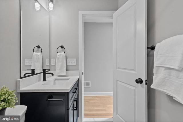 bathroom with vanity, wood finished floors, and baseboards